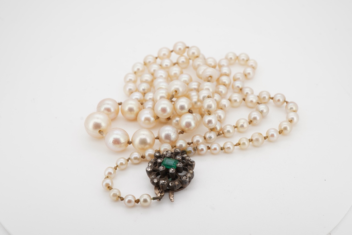 A single strand graduated cultured pearl necklace, with a single stone emerald and rose cut diamond cluster set yellow metal clasp, 64cm.